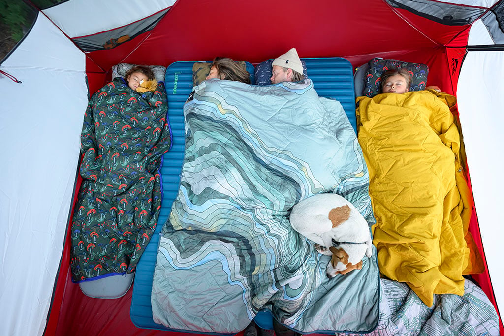 family sleeping in tent with camping blankets