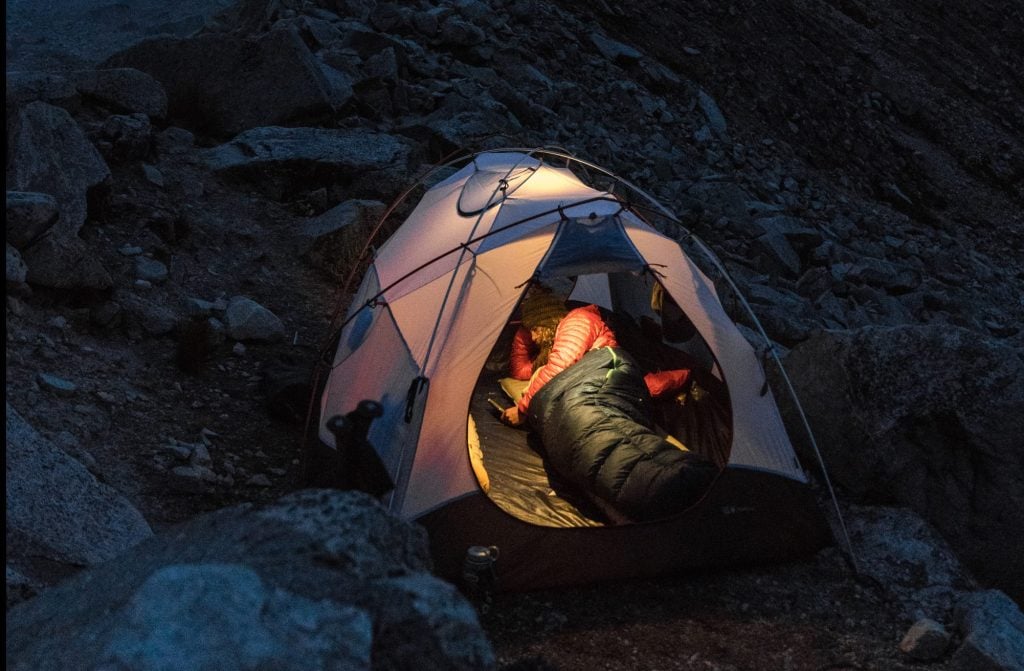 camper in tent in sleeping bag at night