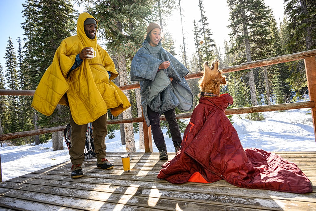 winter camping with dog at cabin in ponchos