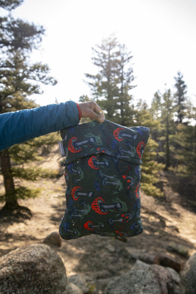 holding a compressible cinch pillow with fun guy print