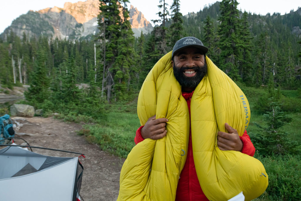 standing at campsite with comfortable sleeping bag on shoulders