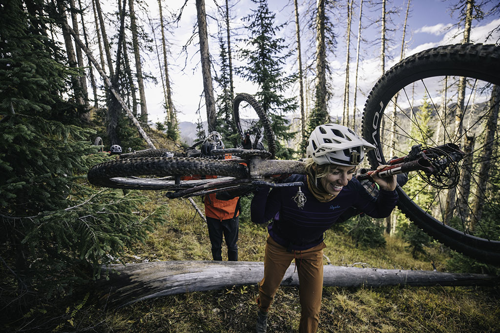 carrying bikes over fallen trees in trail