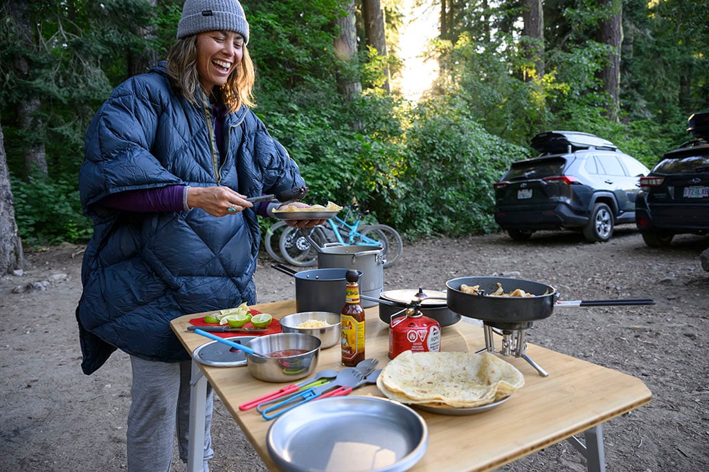 making food at camp in poncho