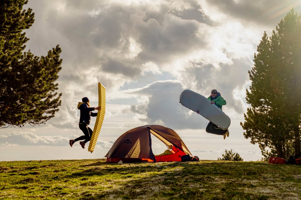 Two people jumping with Therm-A-Rest sleeping pads and an MSR tent.