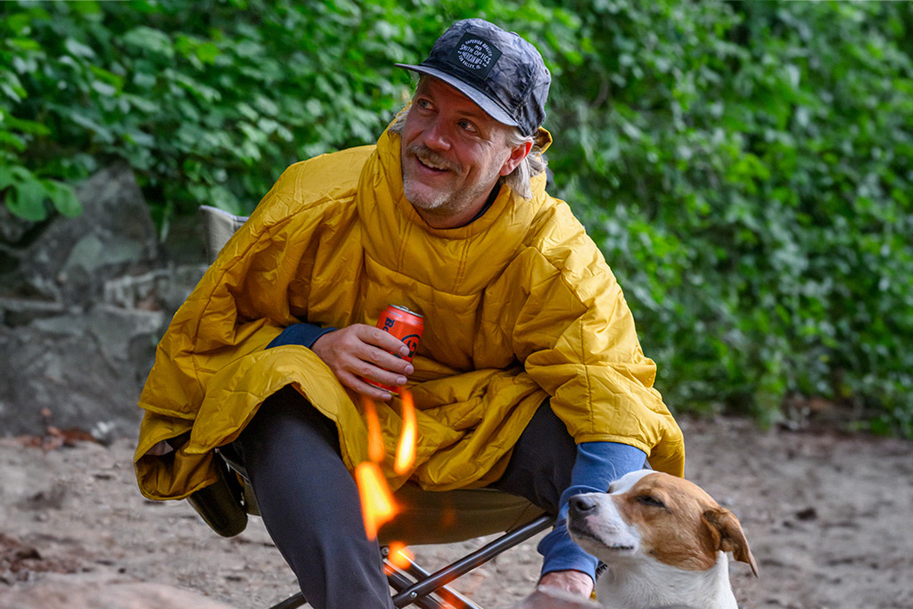 Man sitting in Therm-A-Rest Honcho Poncho with dog