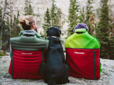 Two people sitting with a dog in Trekker Chairs